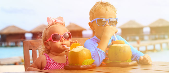 Gutt og jente drikker saft fra kokosnøtter