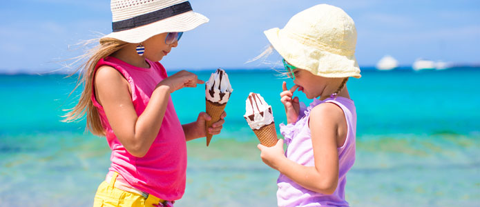 To små jenter spiser is på stranden